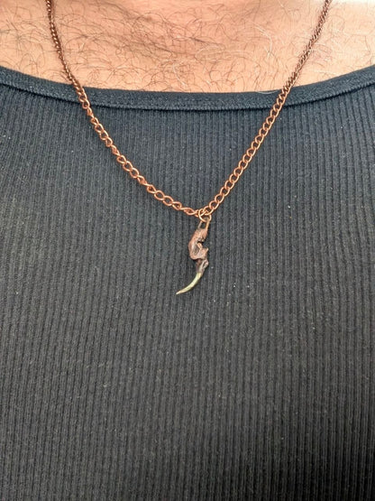 Copper rattlesnake fang pendant worn on chain for scale