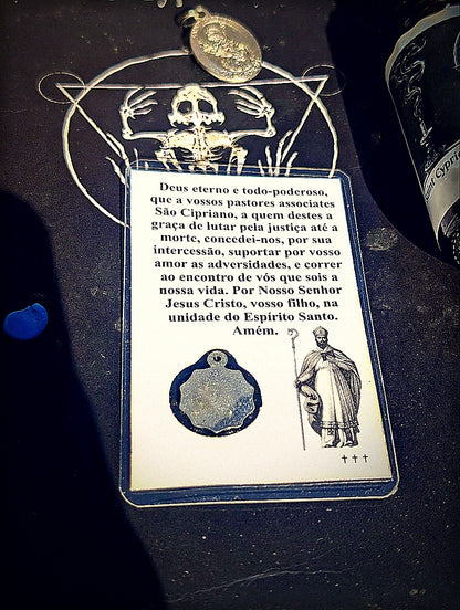 Back of Saint Cyprian prayer card with medal in moody altar light