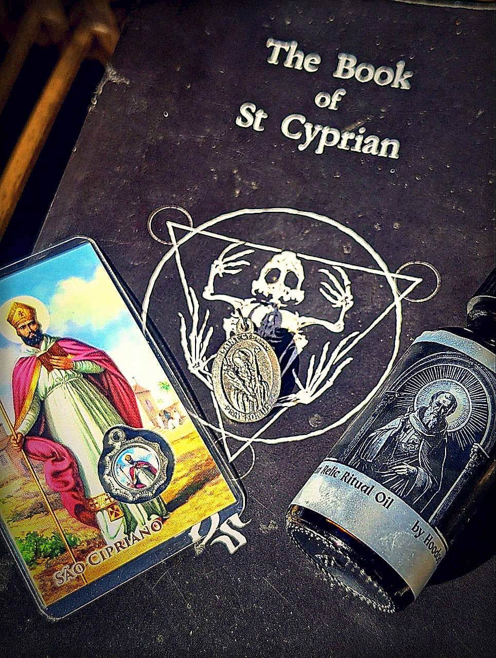 Moody Saint Cyprian feast bundle altar arrangement with prayer card, medal, oil, and book