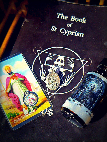 Edgy dark Saint Cyprian bundle product photo with prayer card, oil bottle, medal, and book
